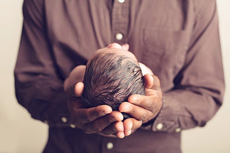 Father holding newborn baby with his hands.