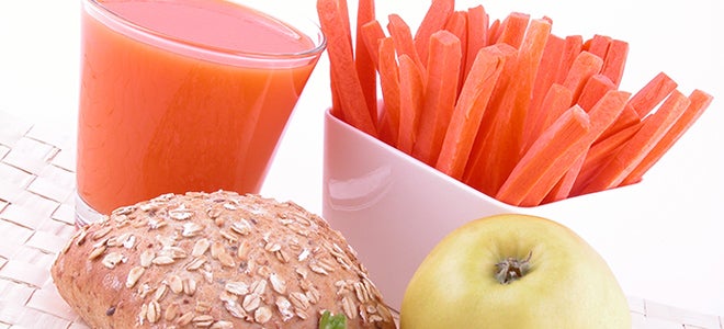 Snack composed of whole wheat bread, an apple, carrot slices, and natural fruit juice.