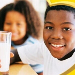 A smiling boy sitting drinking his glass of milk