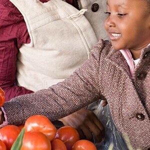 A girl helping her mom choosing fruits and vegetables.