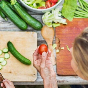 A woman teching a child to prepare vegetables.