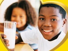 A smiling boy sitting drinking his glass of milk