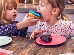 SUGAR: FACT OR FICTION QUIZ Two girls eating donuts together in the kitchen.