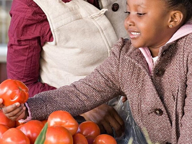A girl helping her mom choosing fruits and vegetables.