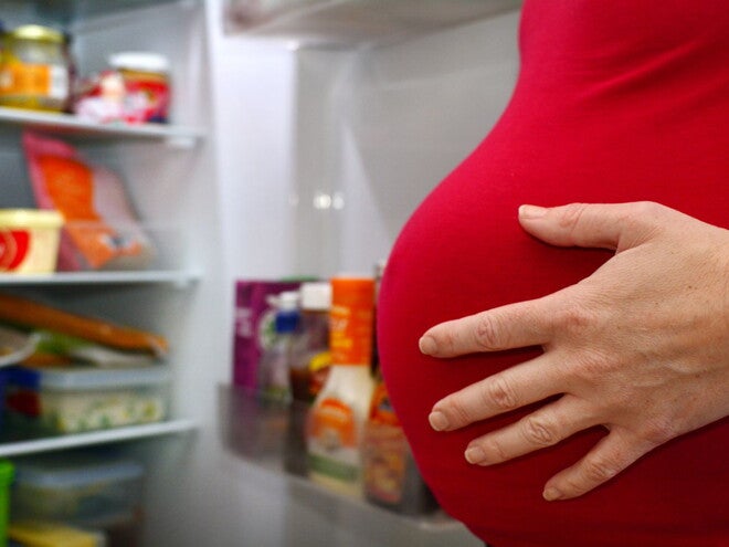 Pregnant woman next to fridge Food cravings during pregnancy